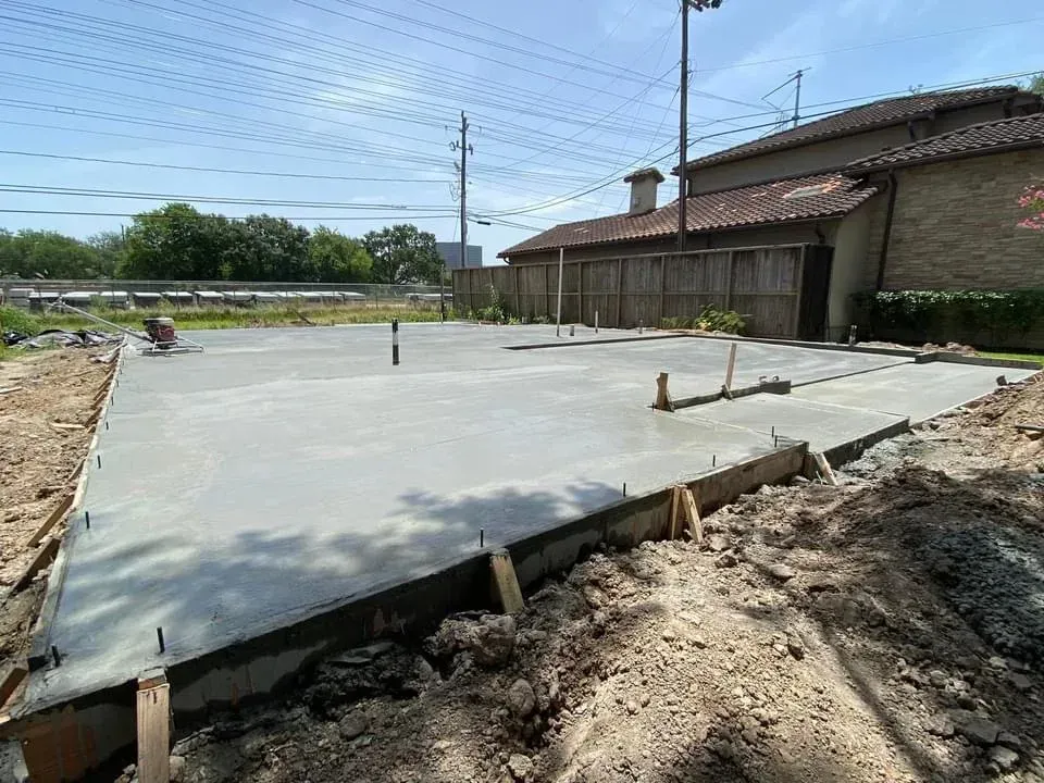 A man is working on a concrete floor in front of a building.