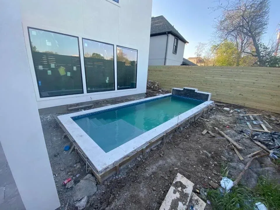A swimming pool is being built in the backyard of a house.