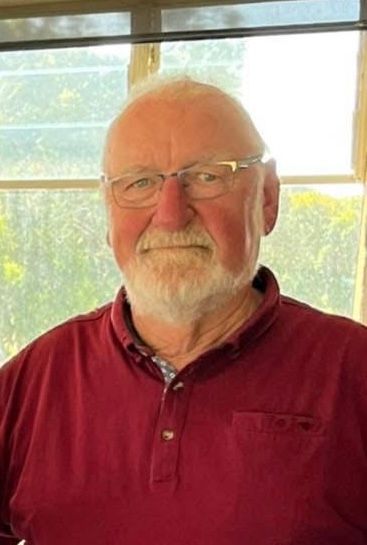 A man with a beard is swinging a golf club on a golf course.