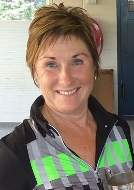 A woman is kneeling down on a golf course holding a golf club.