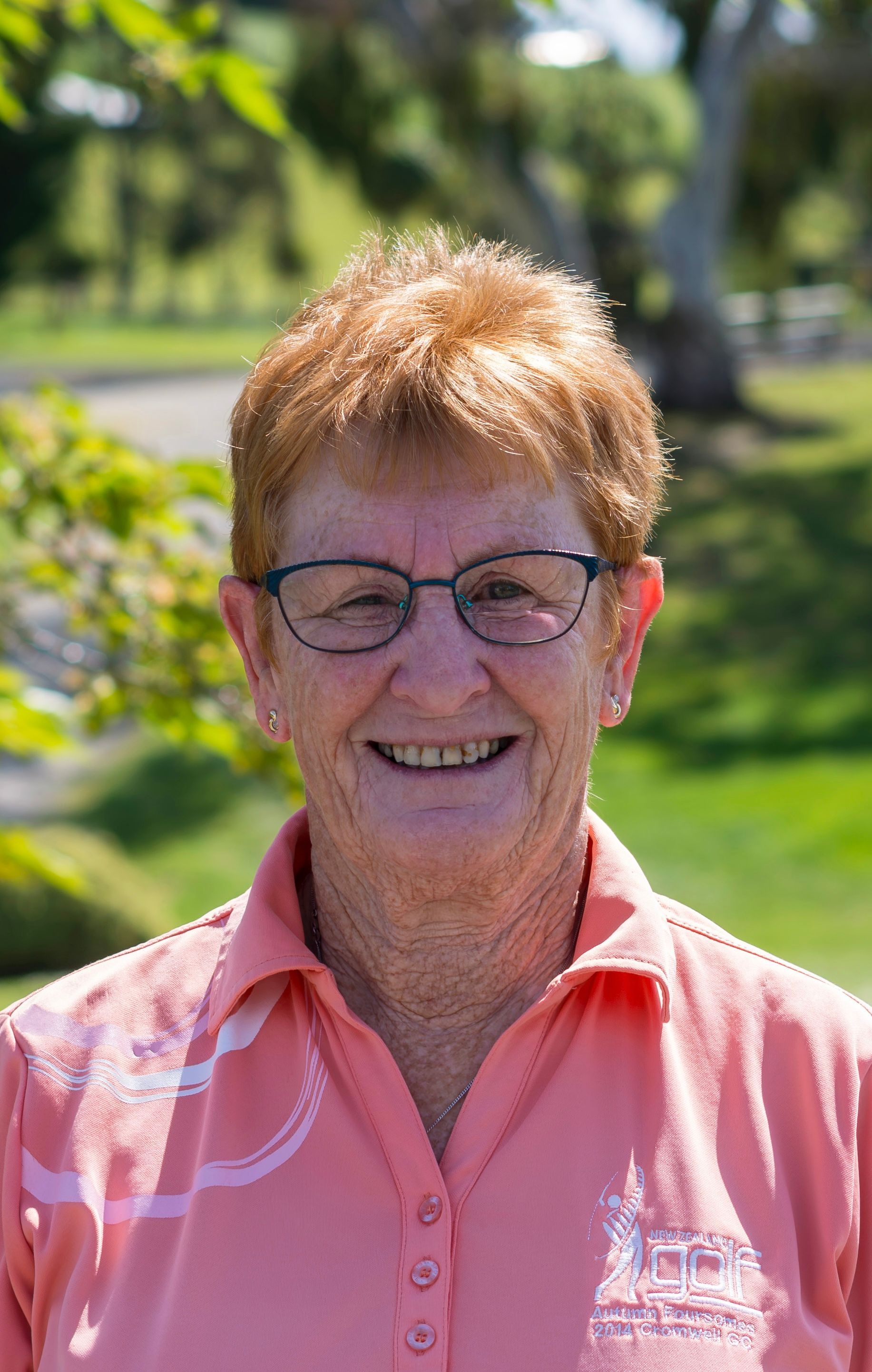 A woman is kneeling down on a golf course holding a golf club.