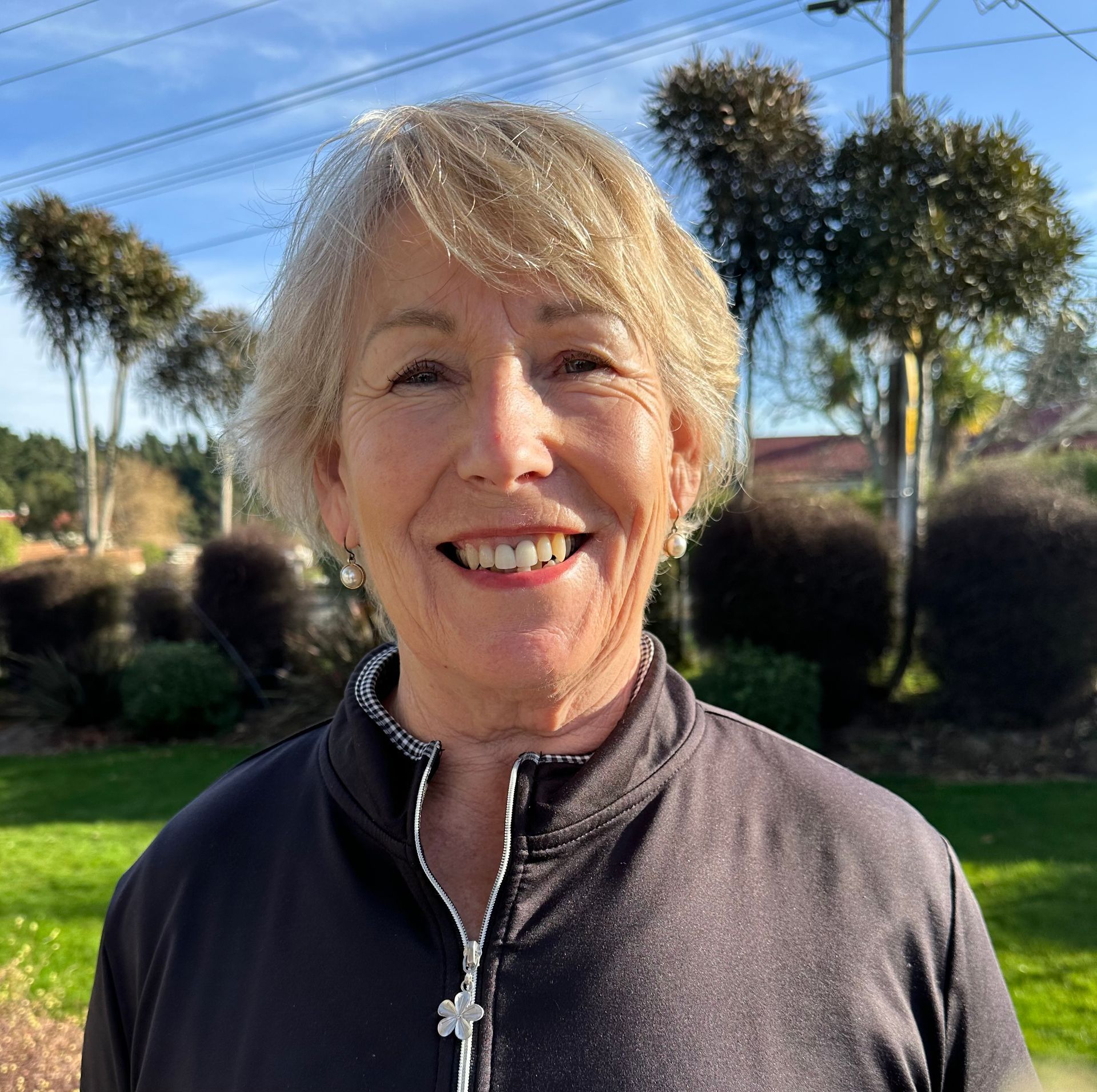 A woman is kneeling down on a golf course holding a golf club.