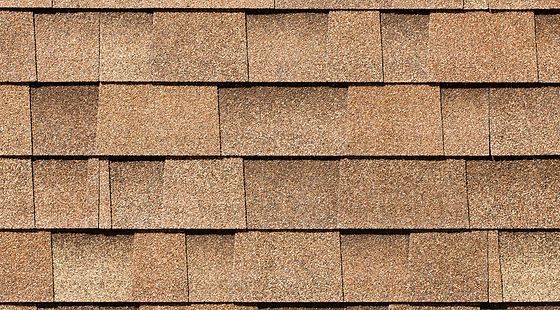 A close up of a row of brown shingles on a roof.