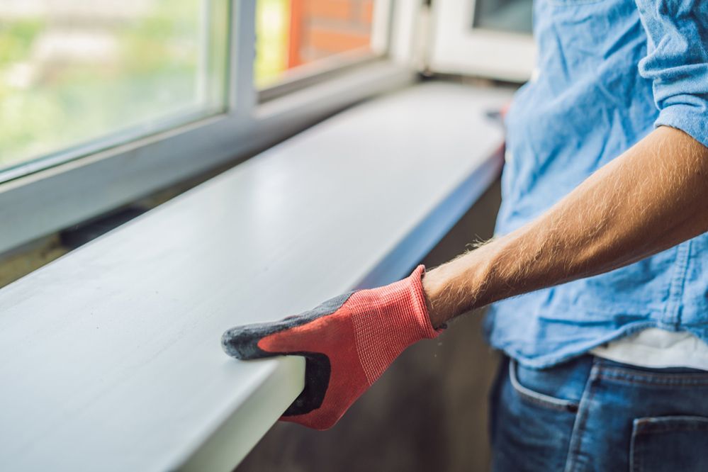 A Man Wearing Red Gloves Is Cleaning A Window Sill — Ace Glass & Aluminium In Grafton, NSW