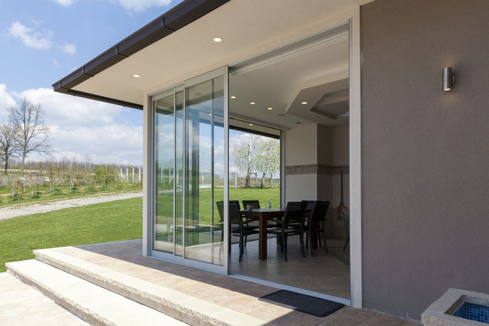 A House With Sliding Glass Doors Leading To A Patio With A Table And Chairs — Ace Glass & Aluminium In Grafton, NSW