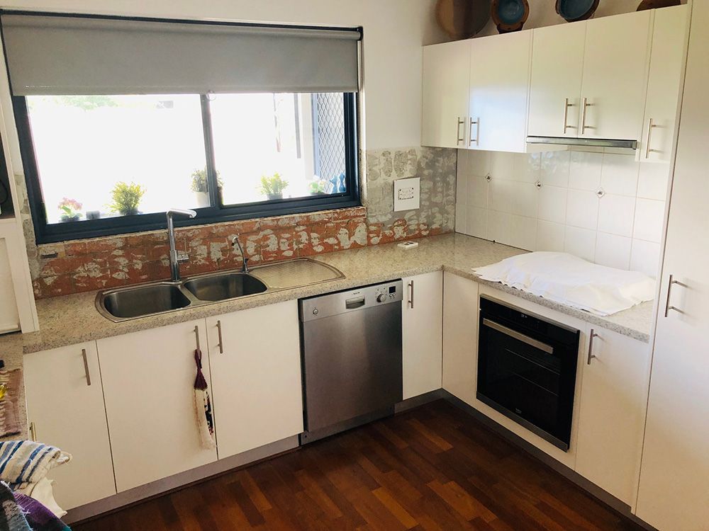 A Kitchen With White Cabinets, Stainless Steel Appliances, A Sink And A Window — Ace Glass & Aluminium In Grafton, NSW