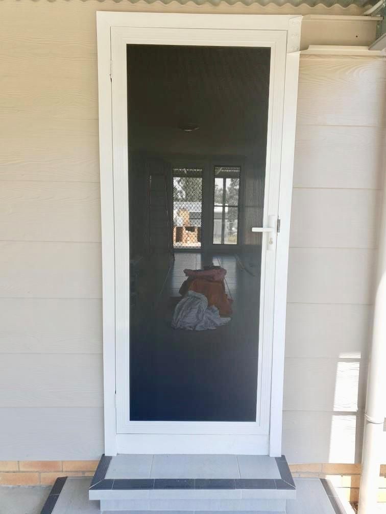 A White Screen Door Is On The Side Of A House — Ace Glass & Aluminium In Grafton, NSW