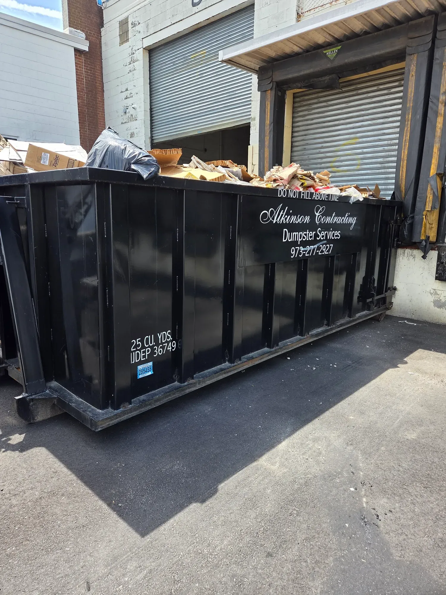 A green dumpster is sitting in front of a house under construction.