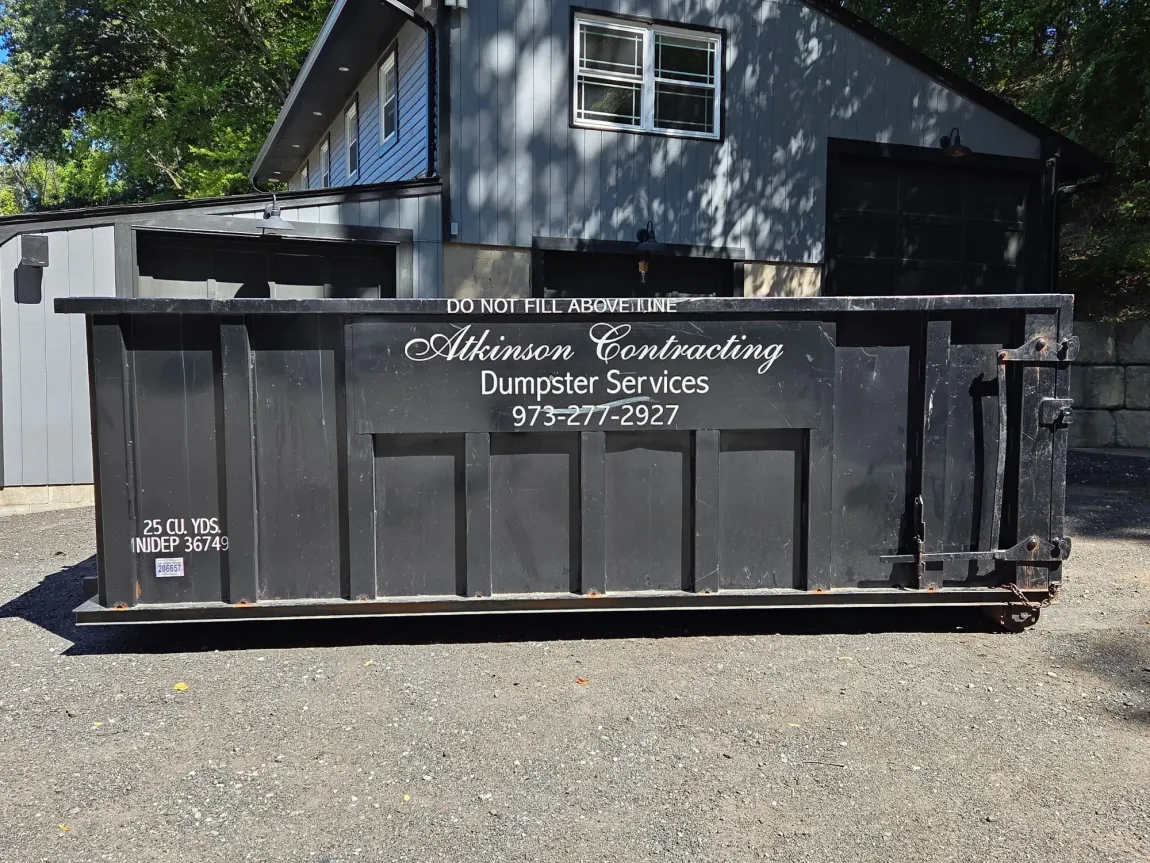 A group of people standing in front of a dumpster.