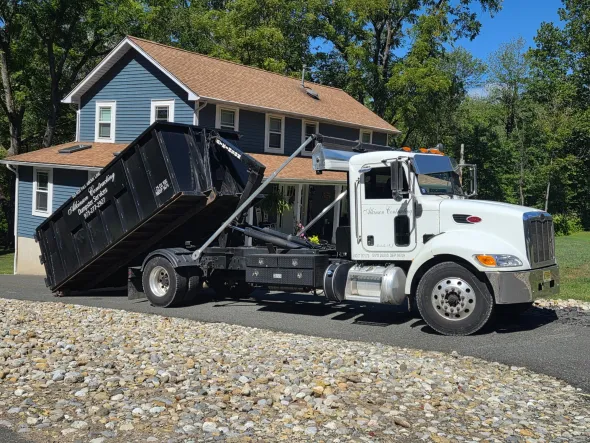 A large yellow dumpster is sitting on the side of a road.