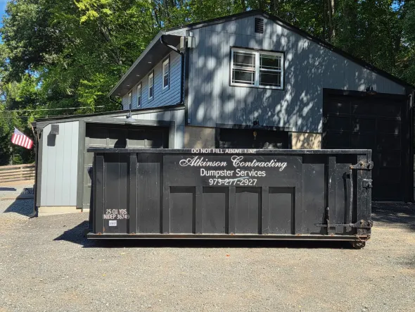 A yellow dumpster is parked in front of a house.