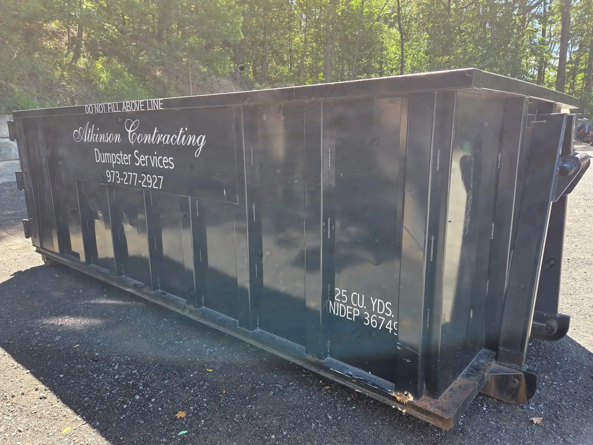 A dumpster is being pulled by a truck on a trailer.