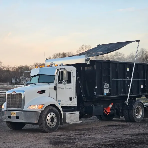 A dumpster truck is parked in front of a building.