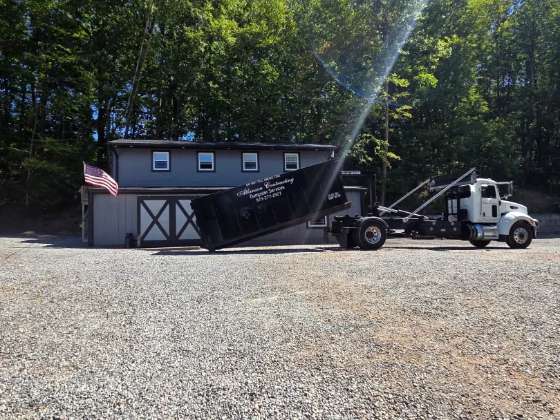 A woman is standing in front of a dumpster.