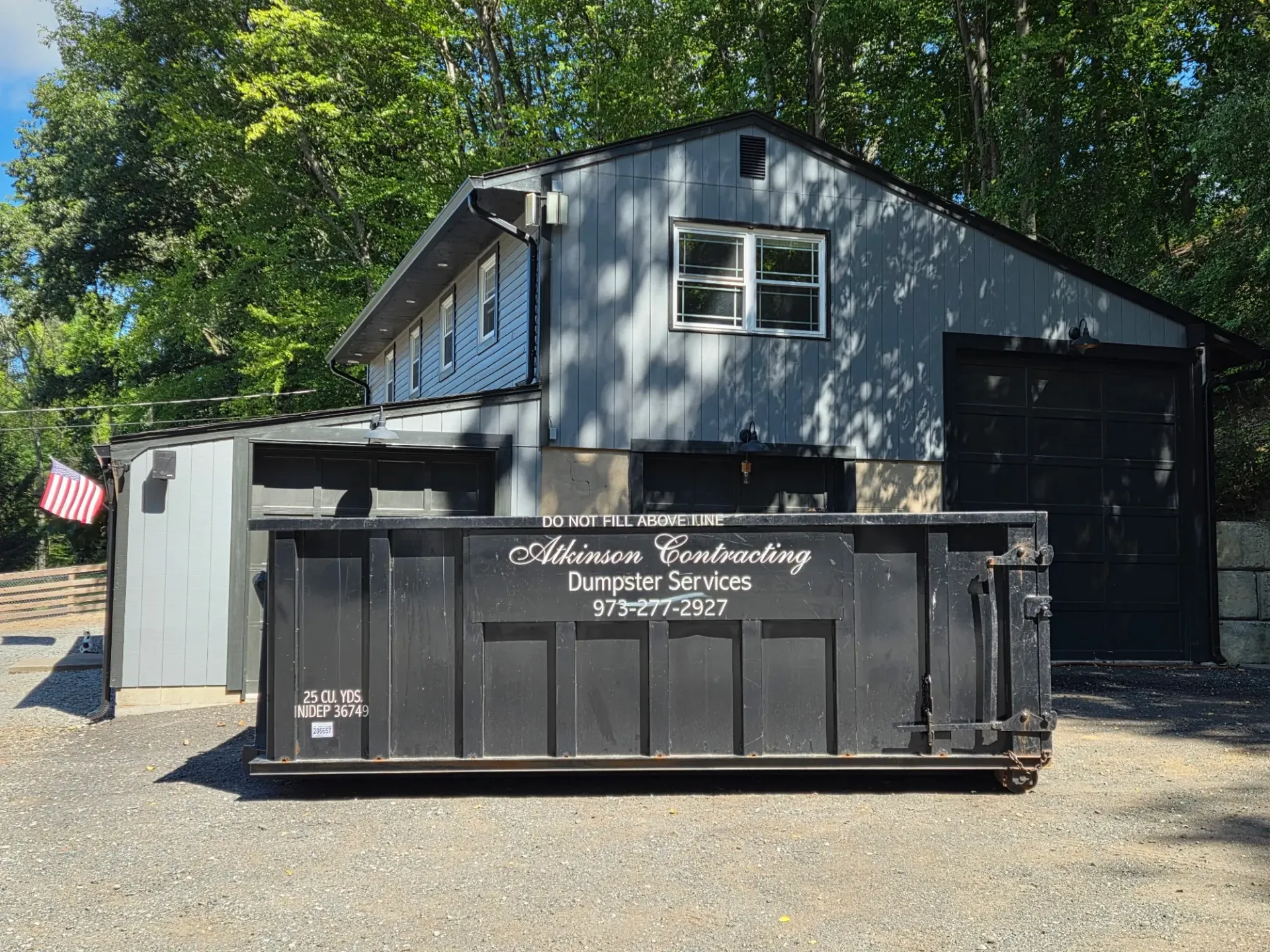 A dumpster is parked in the snow in front of a house.