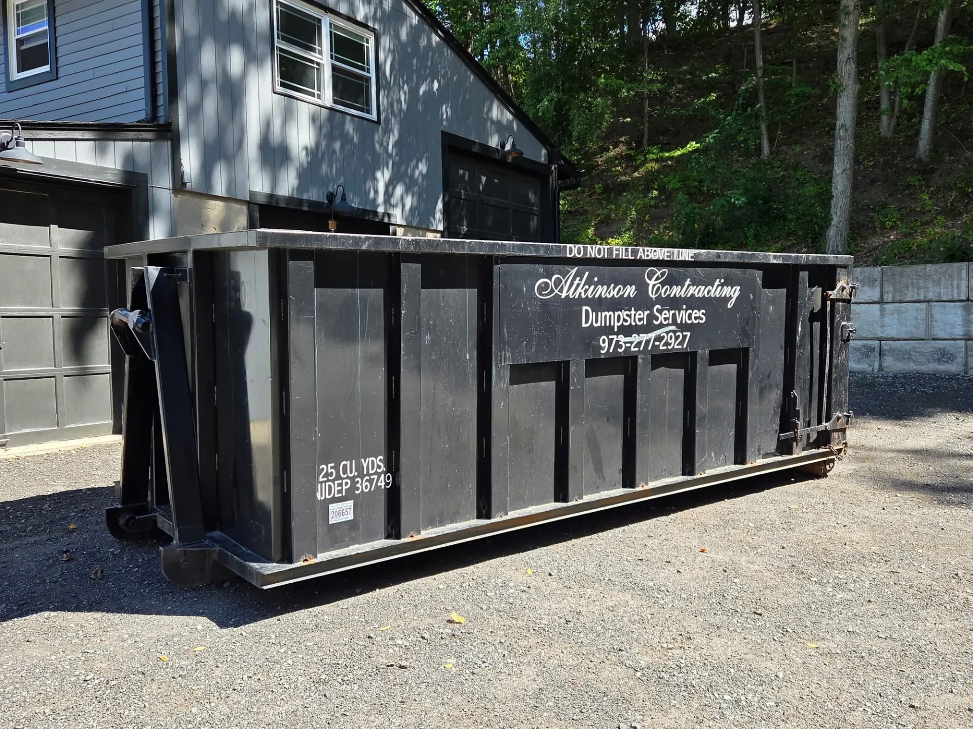 A green dumpster is parked in front of a store.