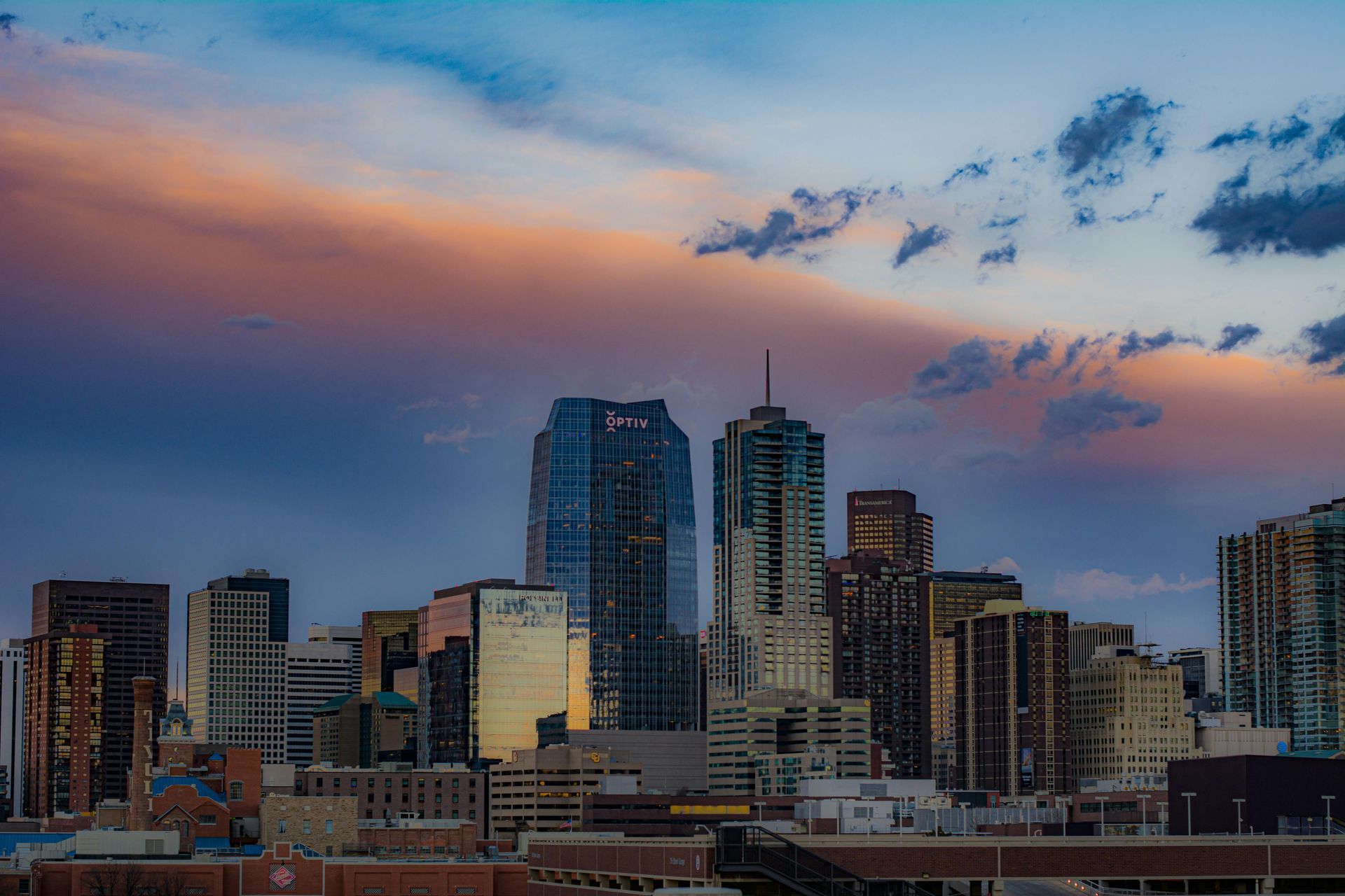 City skyline at dusk with tall buildings under a pink and blue cloudy sky