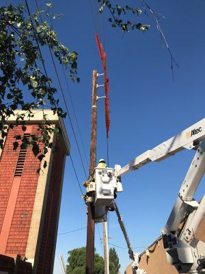 A man in a bucket is working on a power pole.