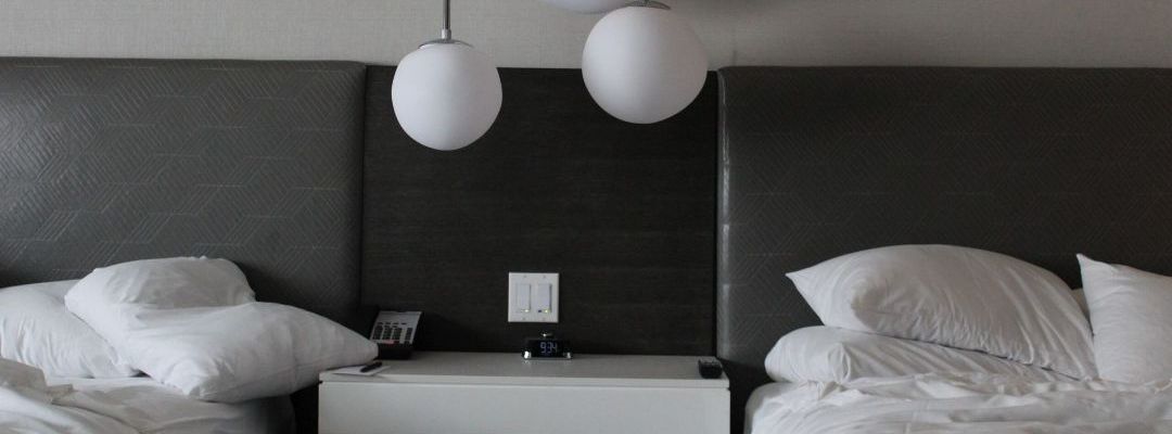 A hotel room with two beds and a nightstand.