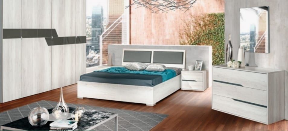 Una camera da letto con un letto, una cassettiera, un comodino e uno specchio.