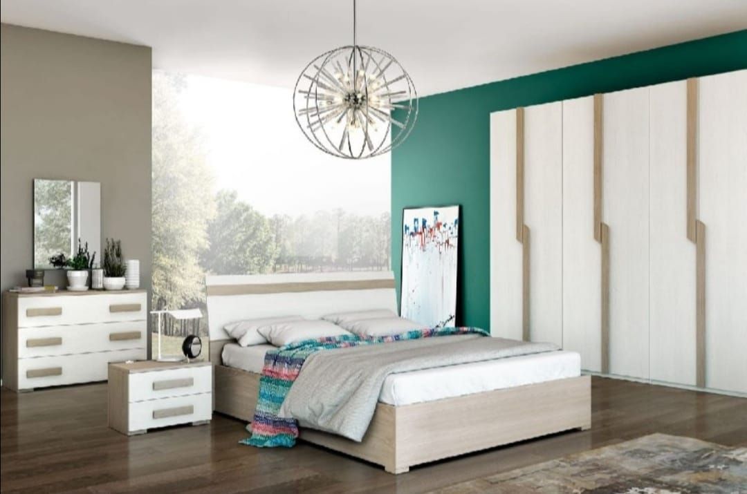 Una camera da letto con un letto, una cassettiera, un comodino, uno specchio e un armadio.