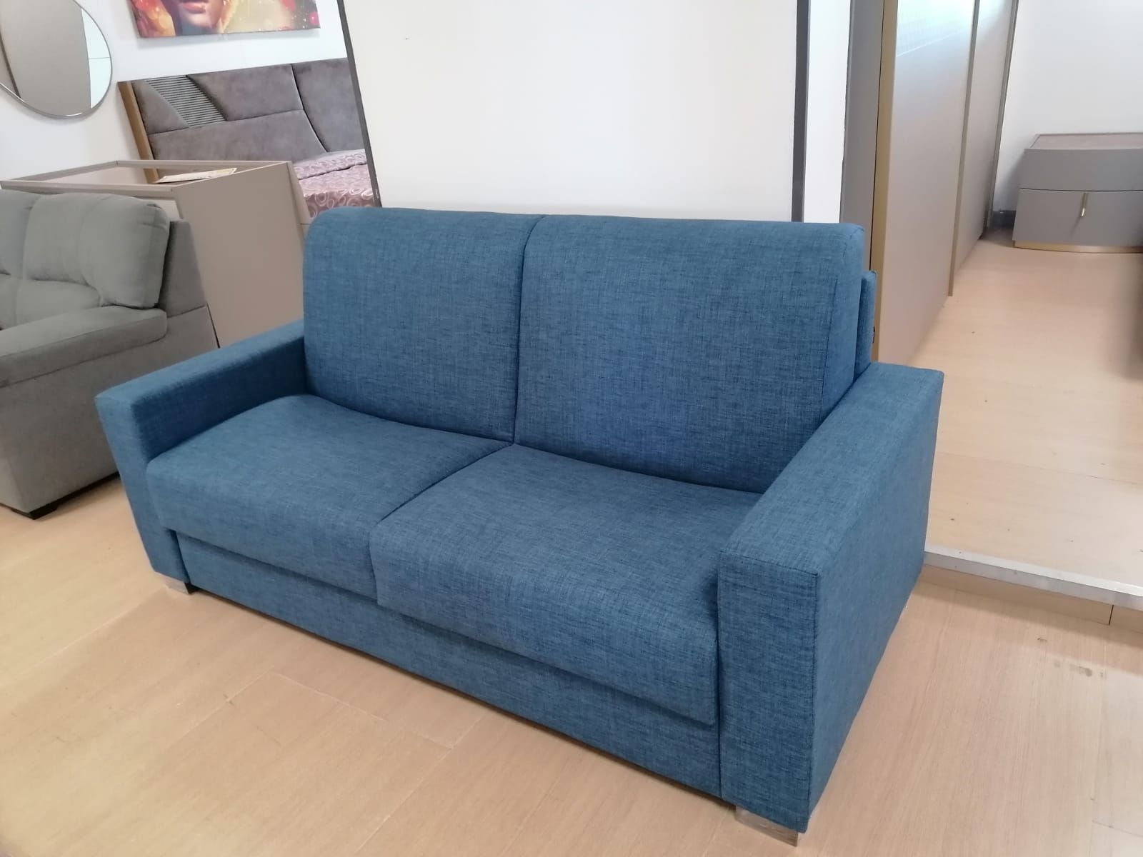 Un divano blu è posizionato in una stanza accanto a uno specchio.