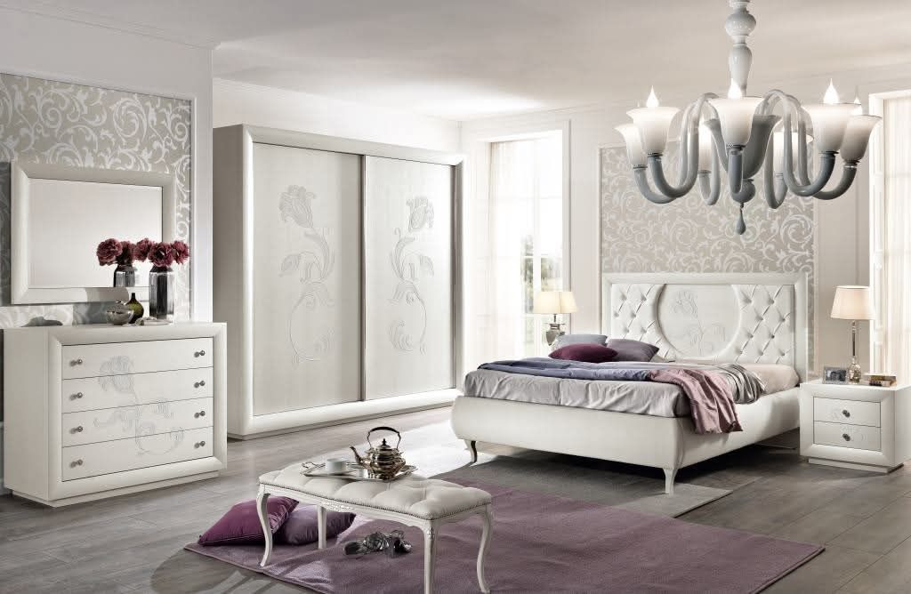 Una camera da letto con un letto, una cassettiera, uno specchio e un lampadario