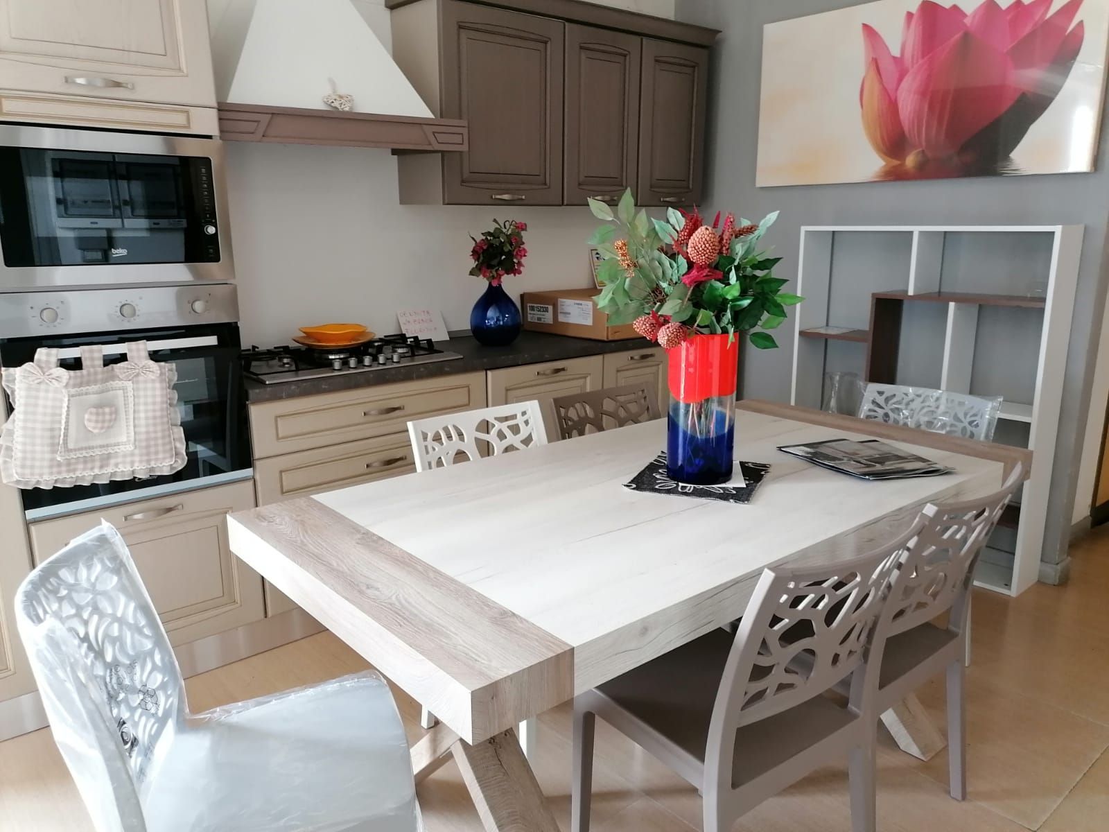 Una cucina con un tavolo, delle sedie e un vaso di fiori.