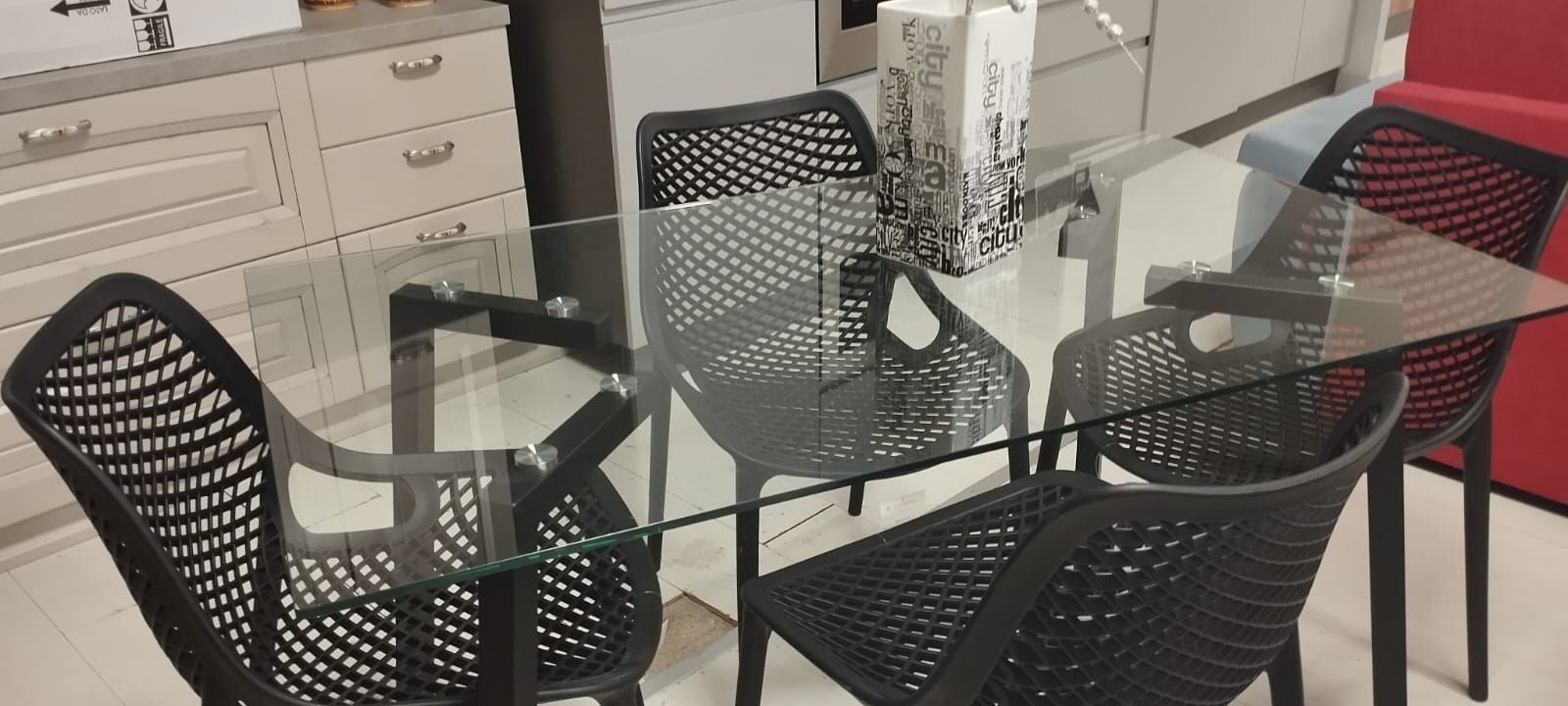 Un tavolo da pranzo in vetro con sedie nere in una cucina.