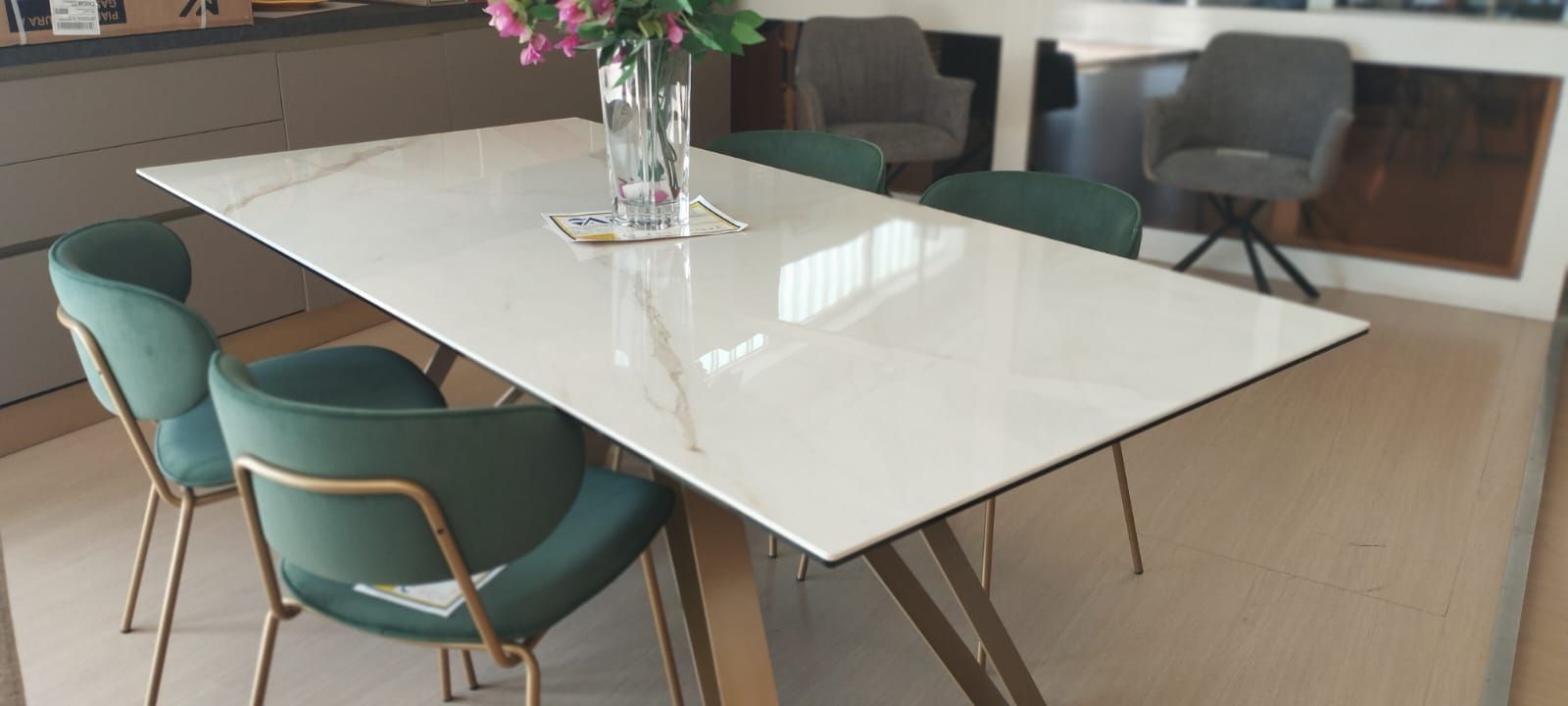 Un tavolo da pranzo con sedie verdi e un vaso di fiori sopra.