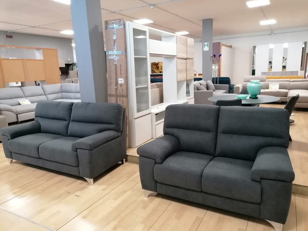 Due divani grigi sono sistemati nel soggiorno di un negozio di mobili.