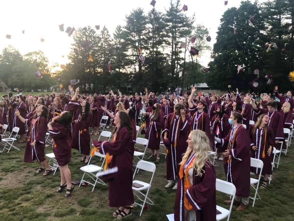 A large group of graduates are throwing their caps in the air