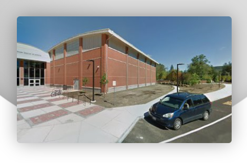 A blue van is parked in front of a large brick building