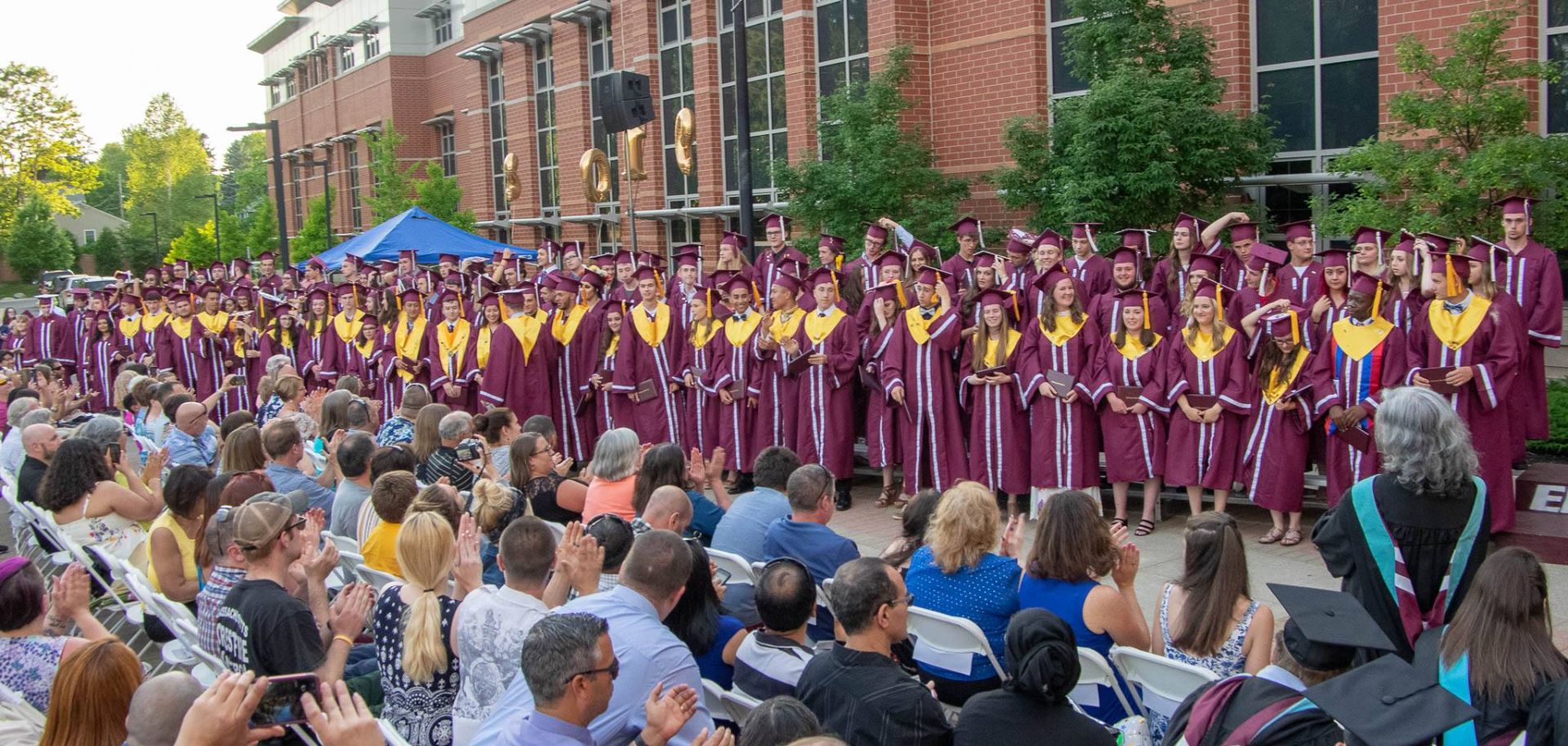 A large group of people are watching a graduation ceremony