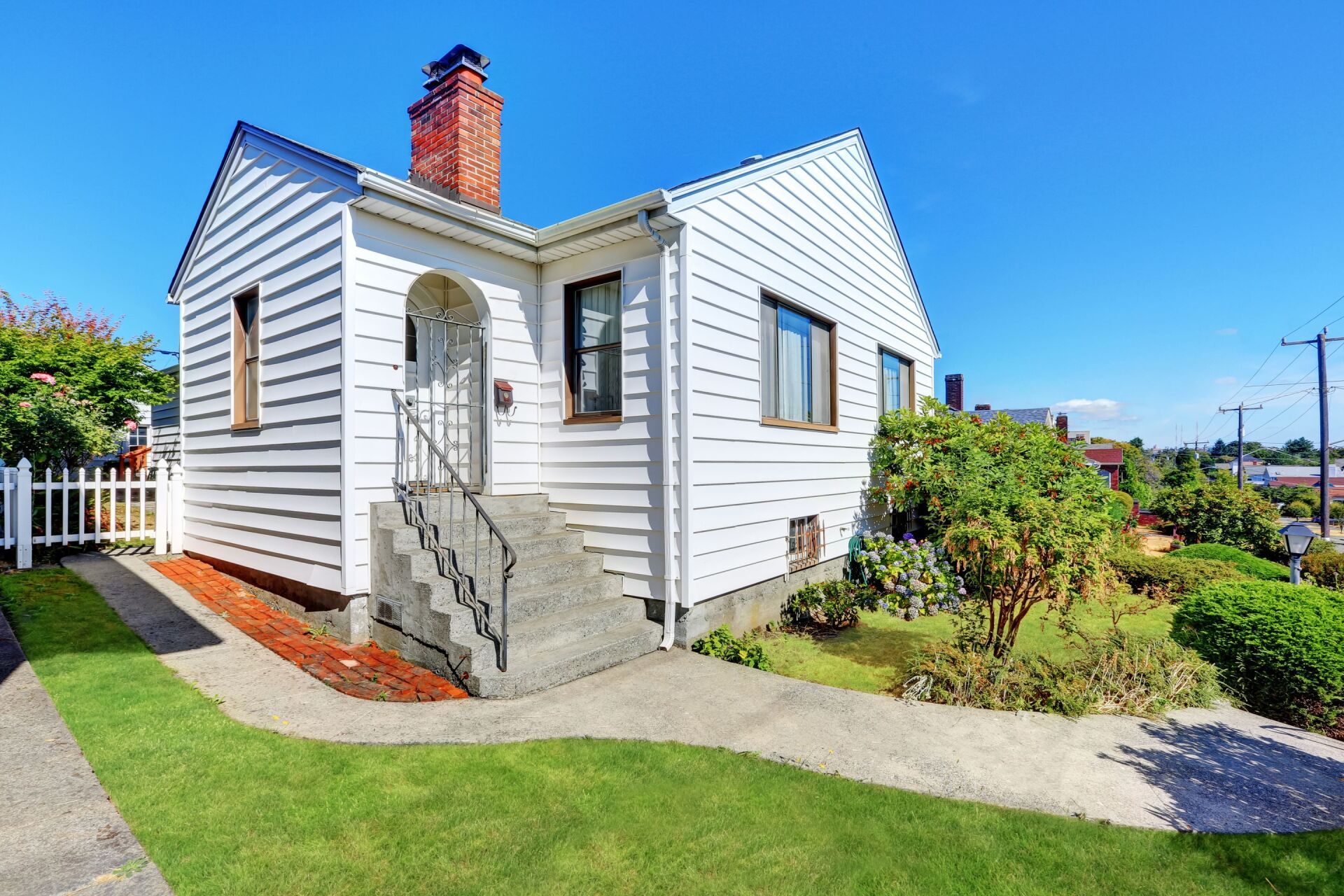 A small white house with stairs leading up to the front door.