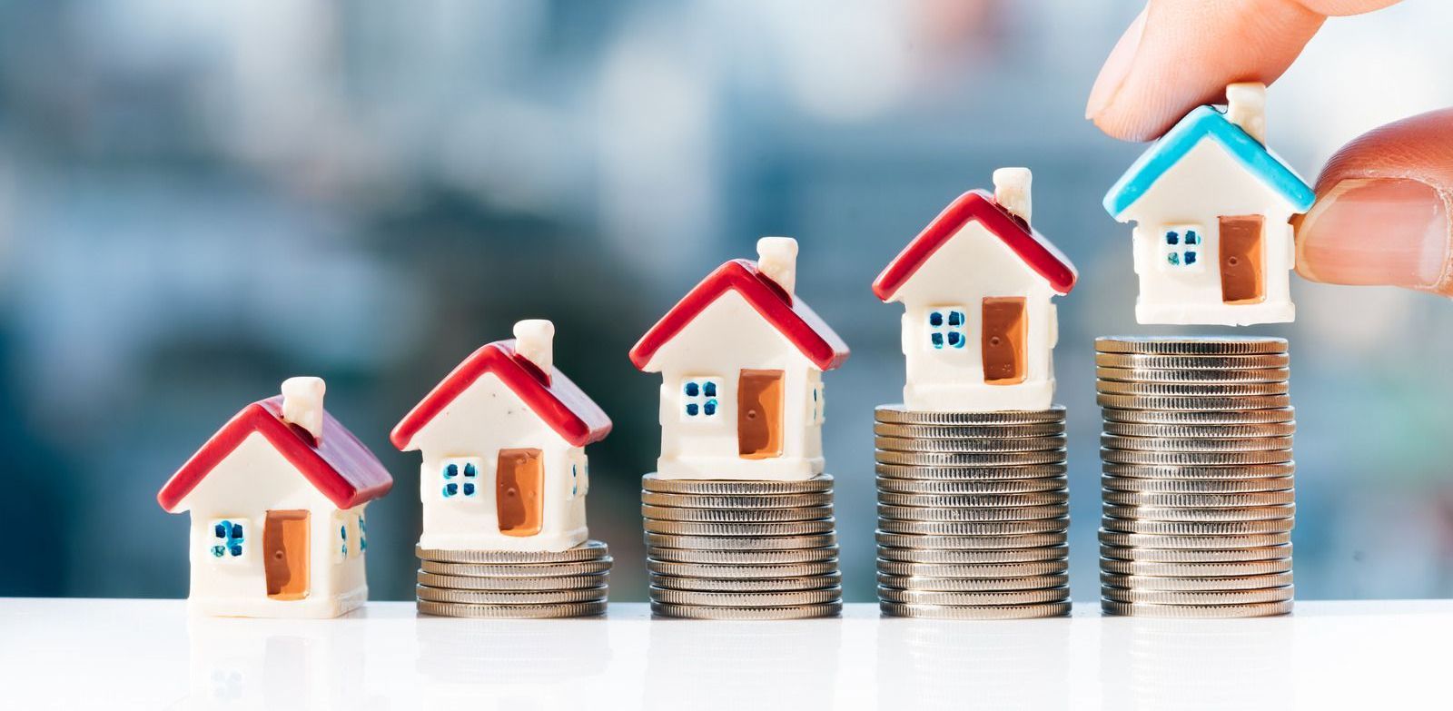 A person is putting houses on top of stacks of coins.