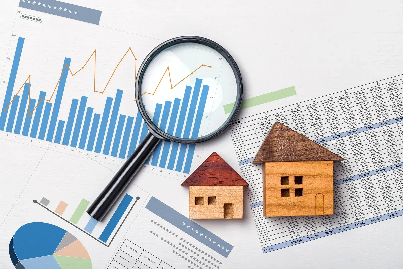 A magnifying glass and two wooden houses are sitting on top of a graph.