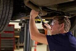Automotive Repair — Auto Mechanic Working Underneath the Car In Garage in Hobart, IN