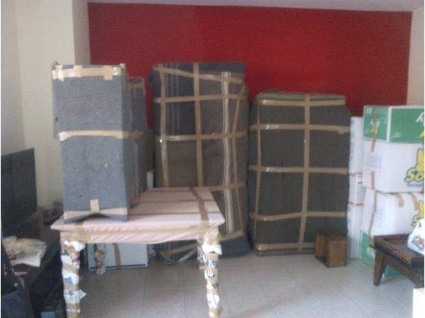 Scatoloni e un tavolino imballati per il trasloco, all'interno di una stanza con una parete rossa.