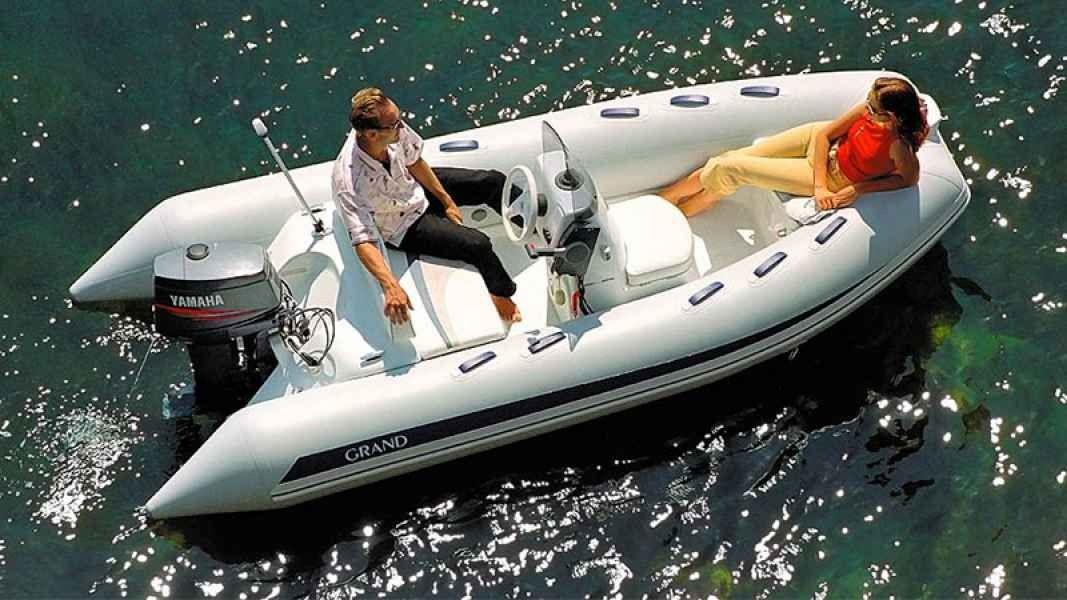 Two people relaxing on a white inflatable boat floating on sparkling green water