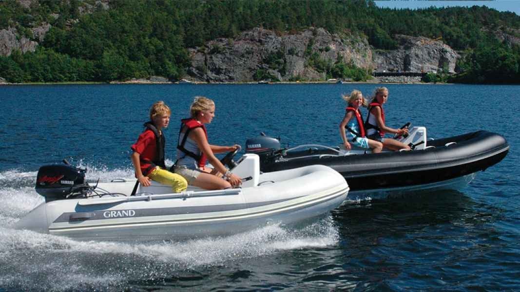 Two inflatable boats with riders speeding across a lake near a forested shore