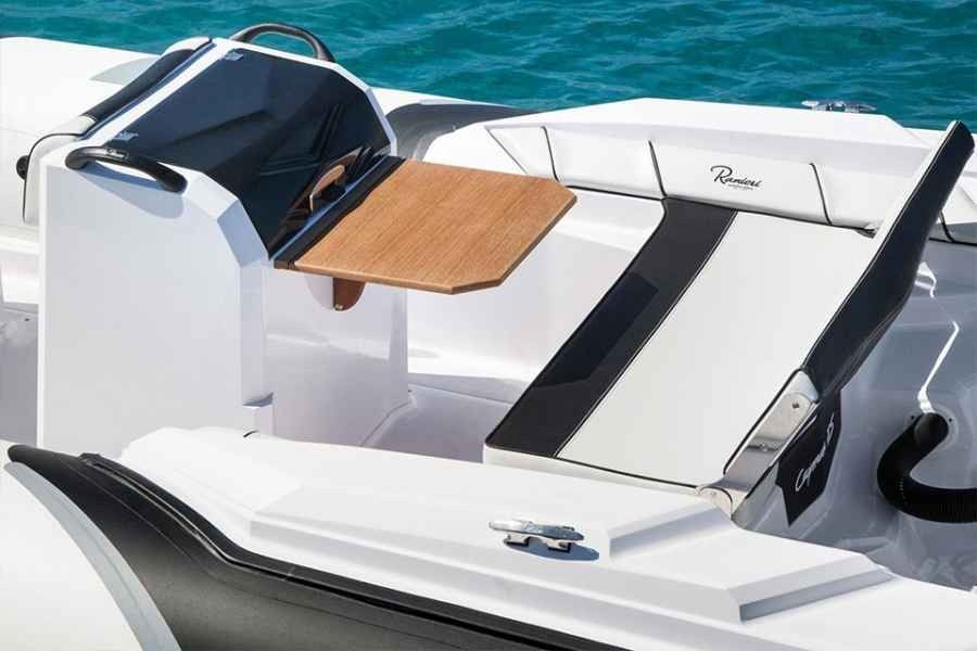 White and black boat seating area with a folded canopy and small wooden table on deck