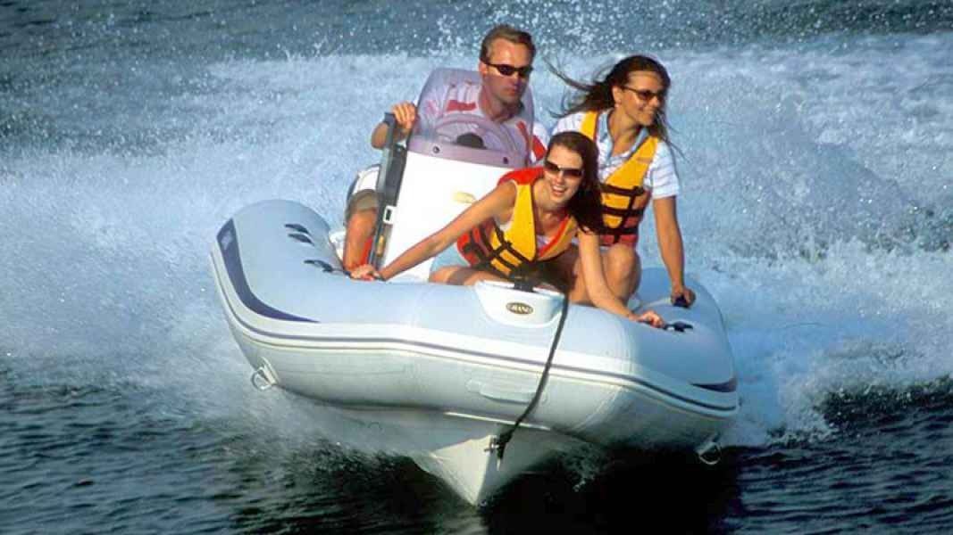 Three people ride a grand golden line 380 speedboat through splashing water, wearing life jackets.