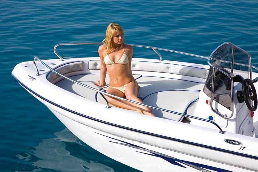 Woman in a white bikini on a small white ranieri voyager 17 boat in calm blue water
