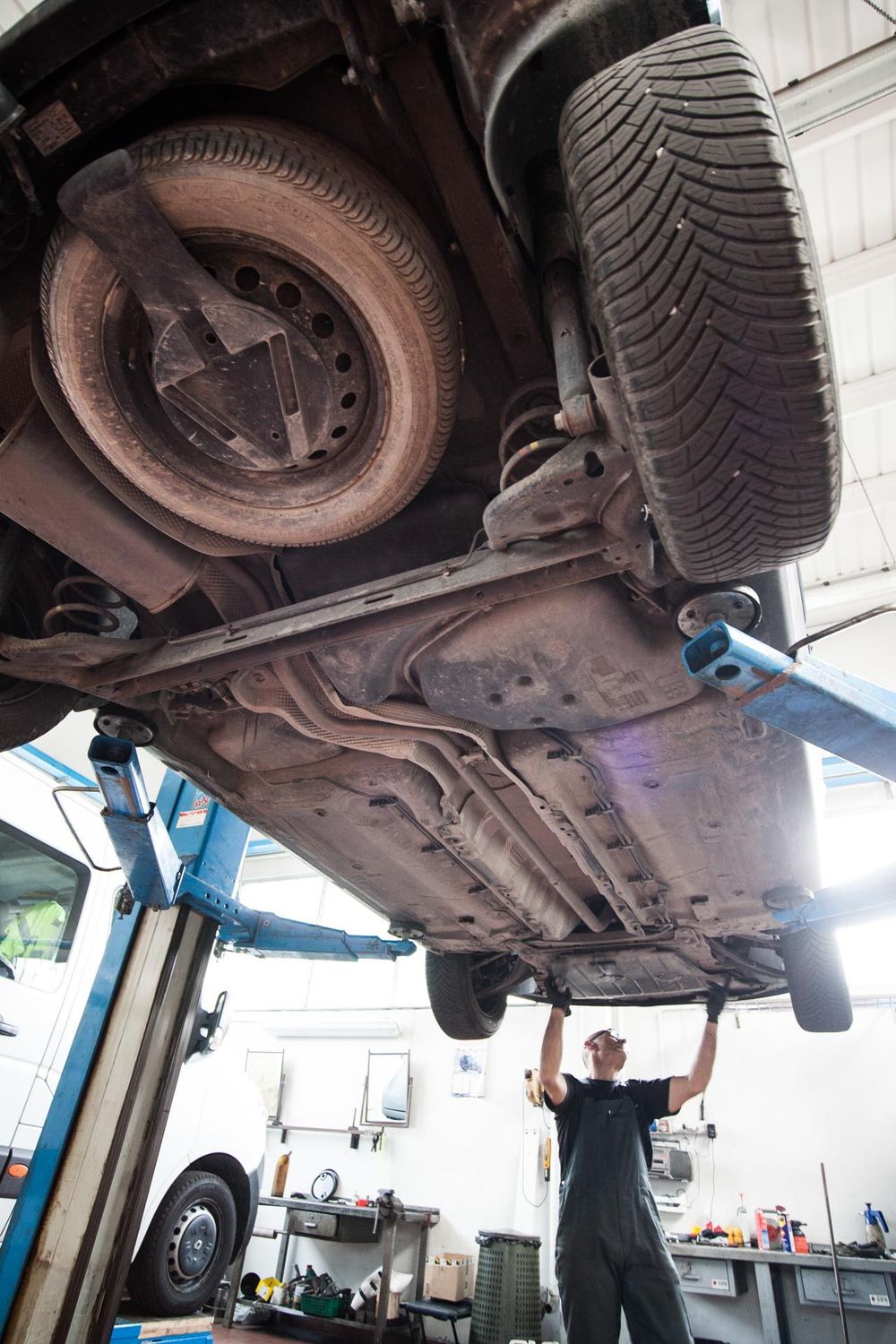 Un'auto nera con il cofano aperto, una batteria e un blocco sul motore in un'officina.