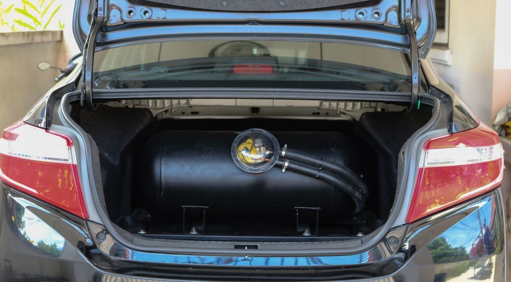 Fiat 500 bianca decappottabile in garage con attrezzi su una superficie in legno. Tettuccio apribile aperto, attrezzi sistemati.