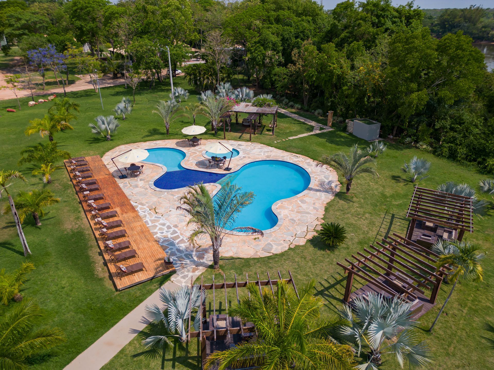 Uma vista aérea de uma grande piscina cercada por palmeiras.