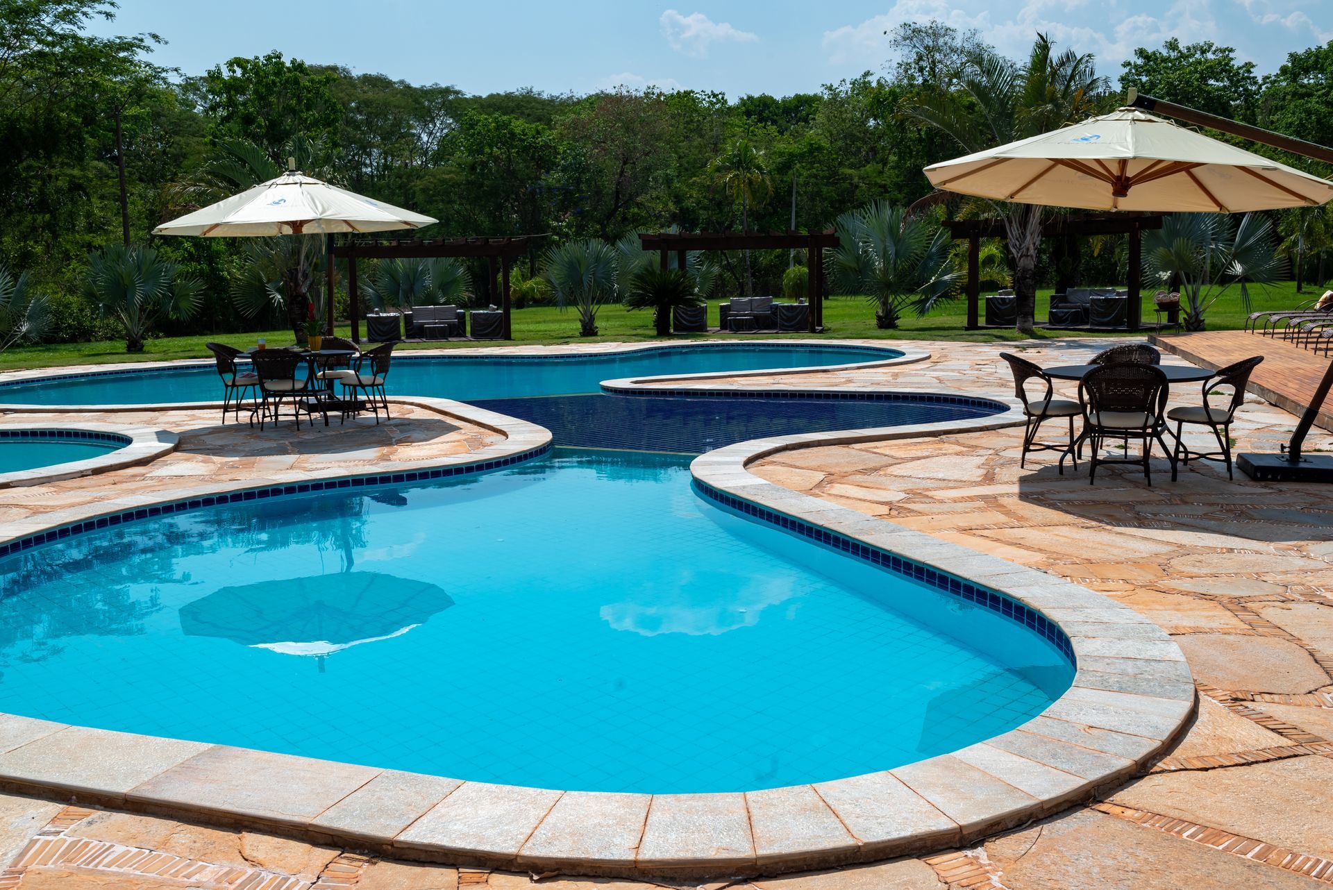Uma grande piscina com guarda-sóis e cadeiras ao redor