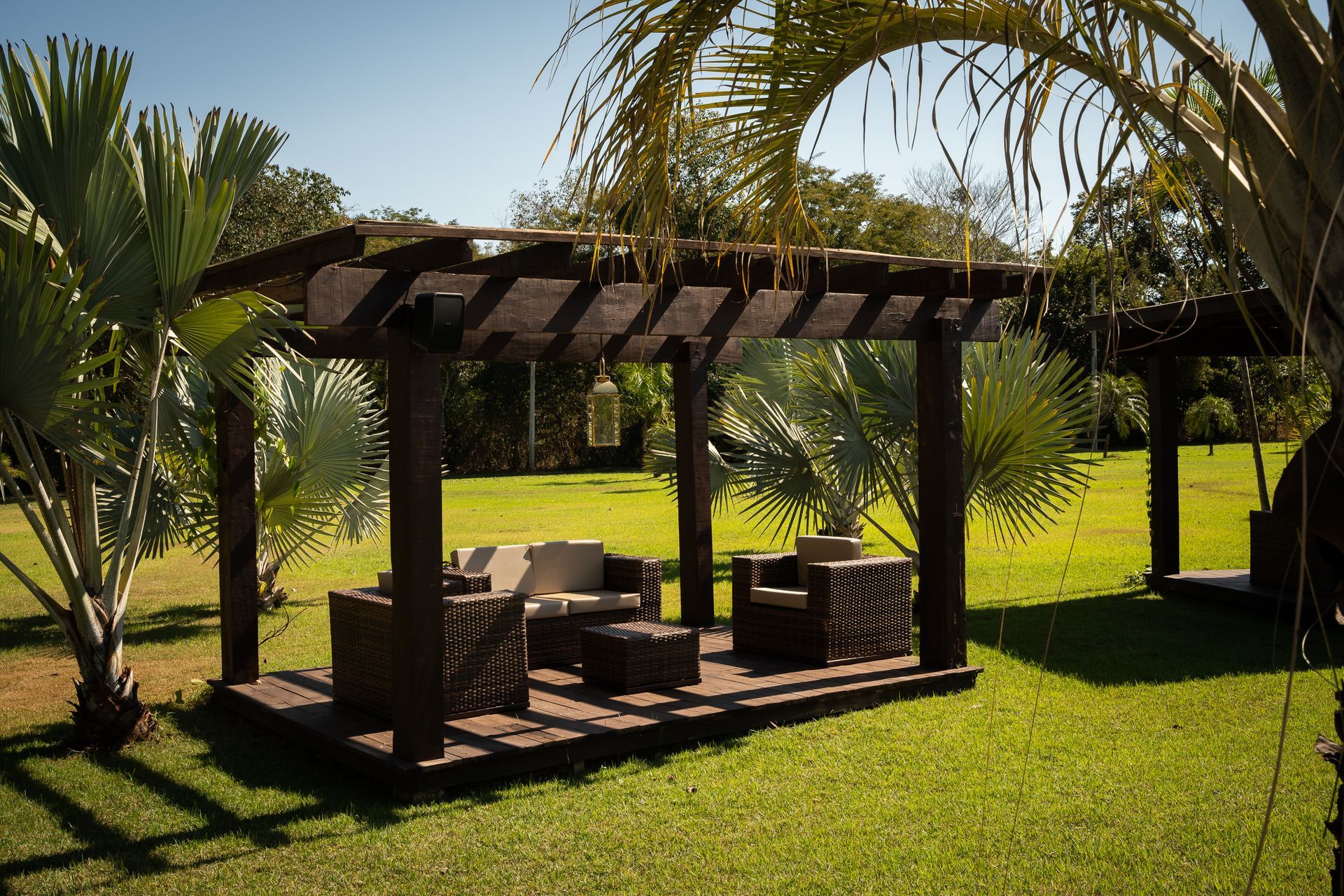 Uma pérgula com um sofá e cadeiras embaixo dela