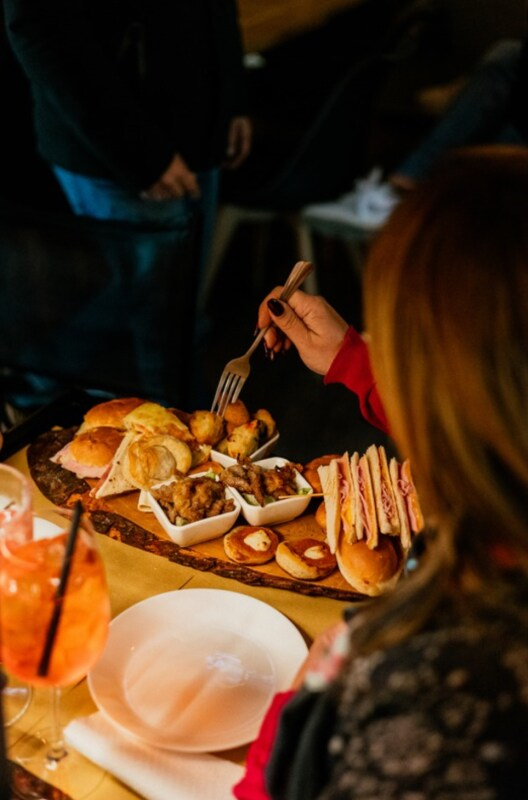 Cornetti tagliati a metà, farciti con frutti di bosco, panna, curry e cioccolato, sullo sfondo di un murale.